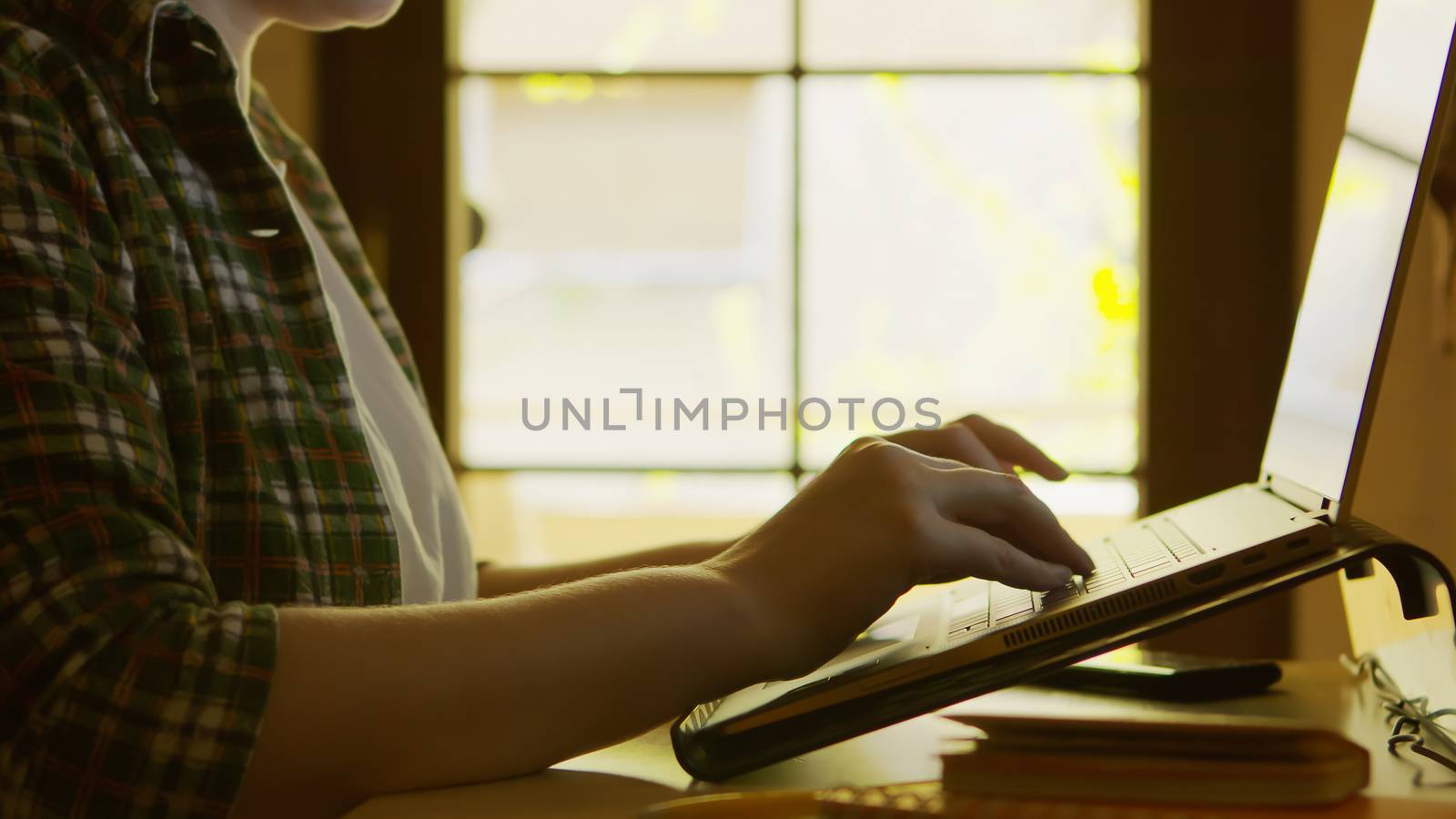 Silhouette of freelancer woman working from home on modern laptop.