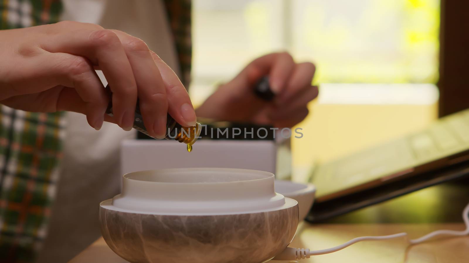 Woman adds essential oil into diffuser by DCStudio