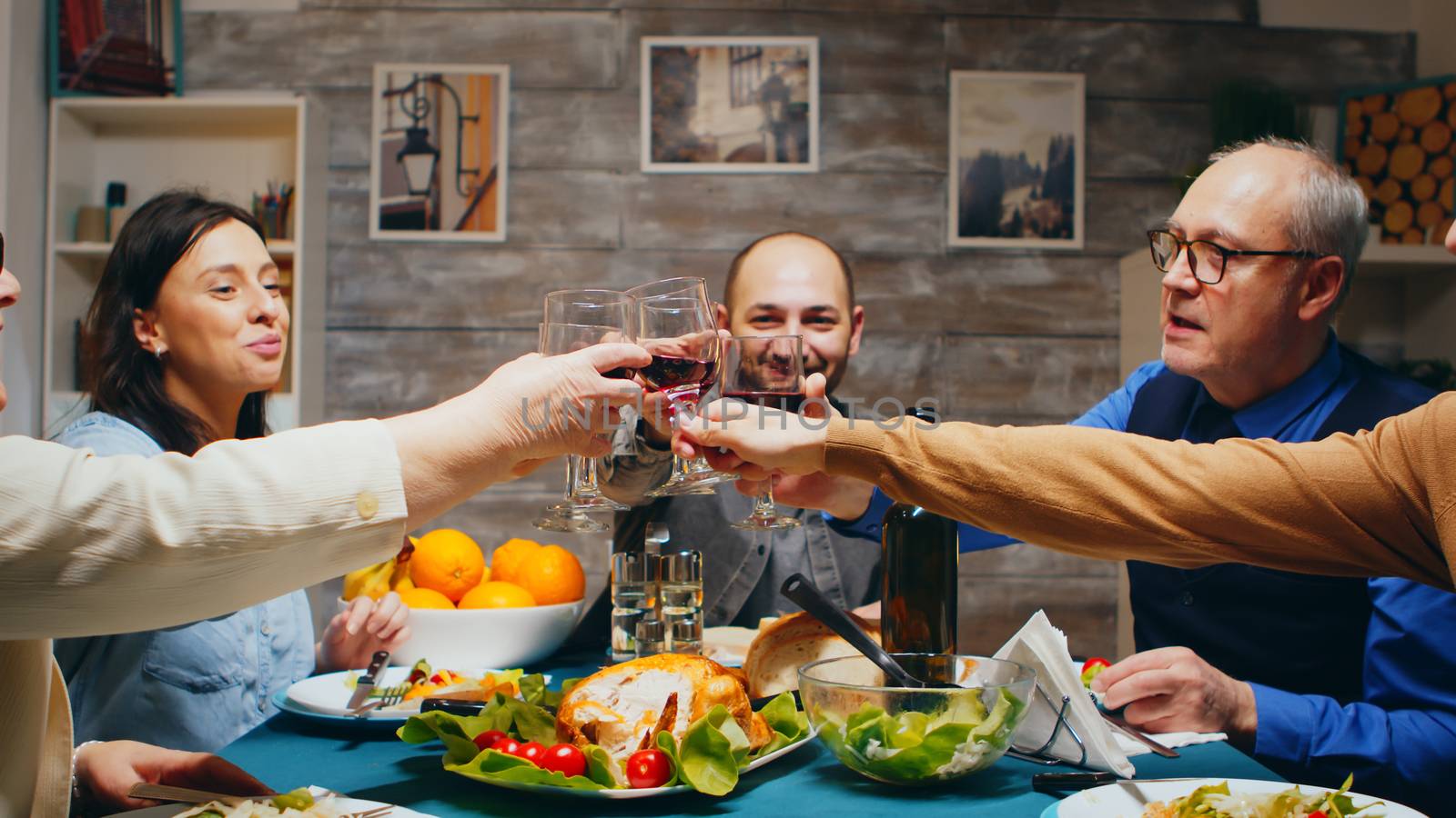 In the evening family gathered for dinner clinking glasses of wine making a toast.