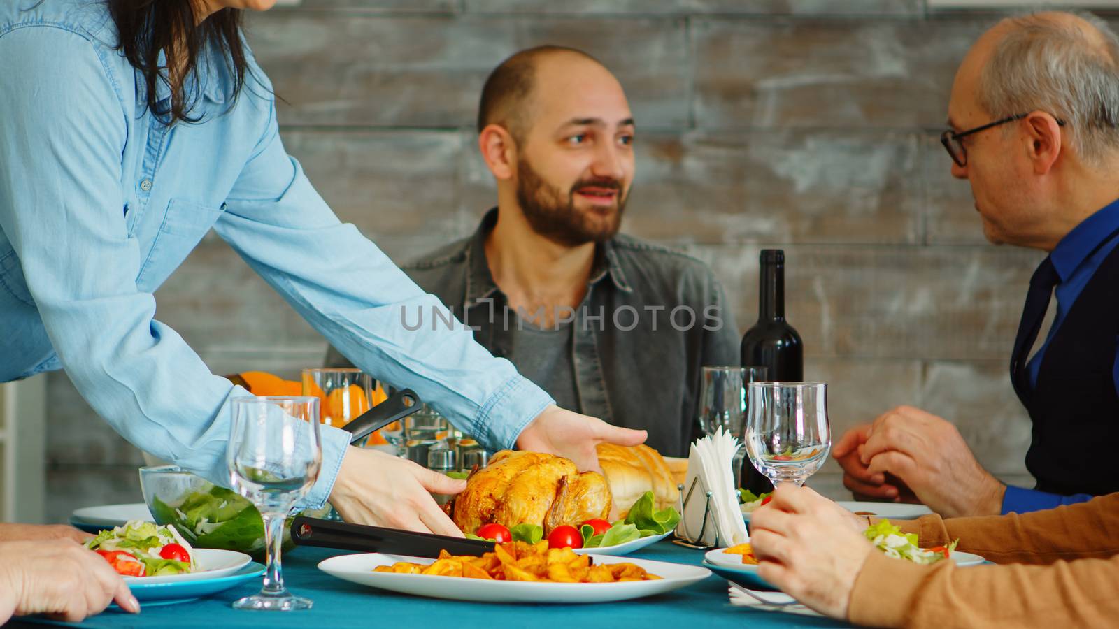 Young wife putting tasty chicken on the table by DCStudio