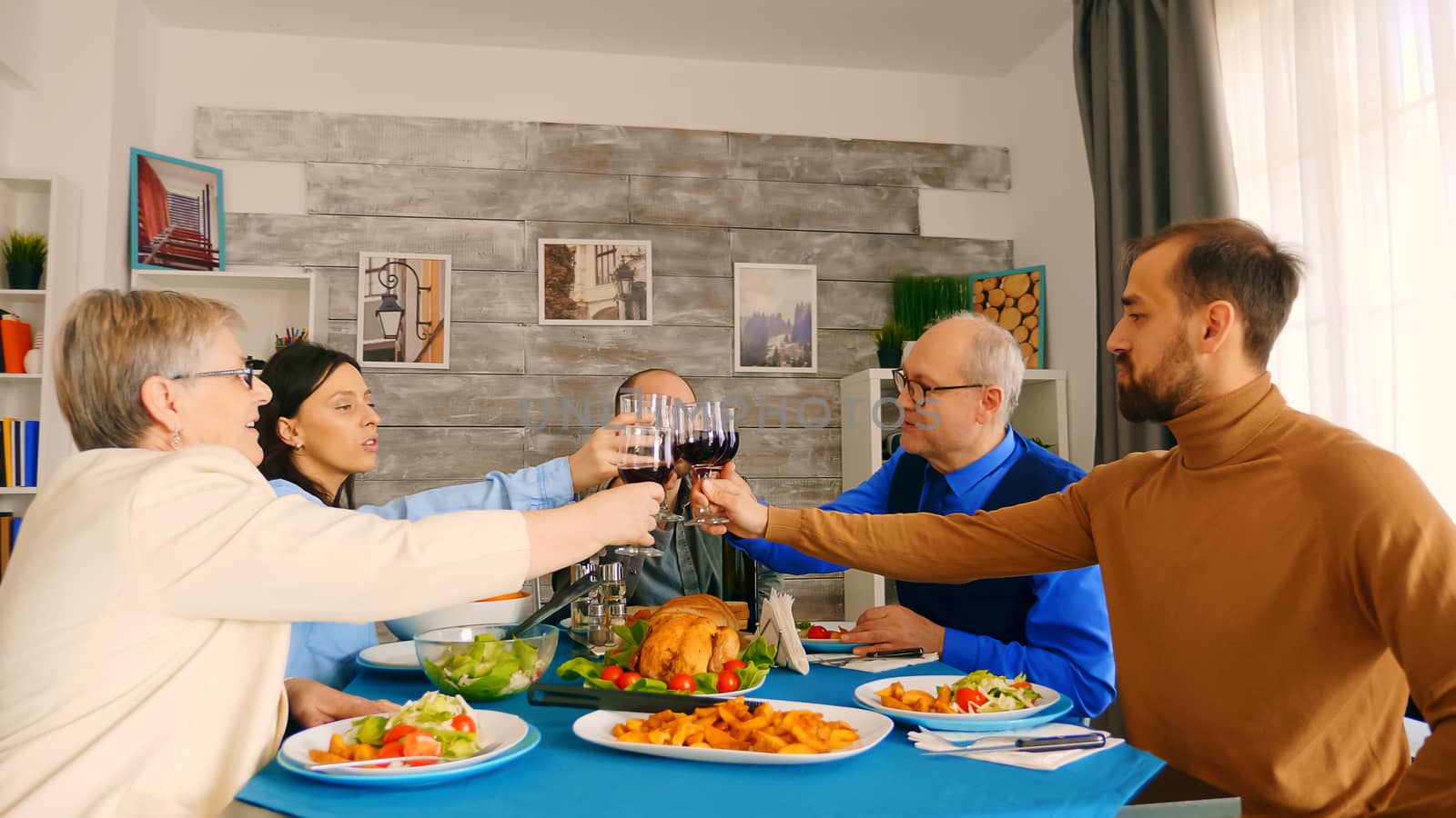 Young man clinking a glass of wine with his family while enjoying dinner.