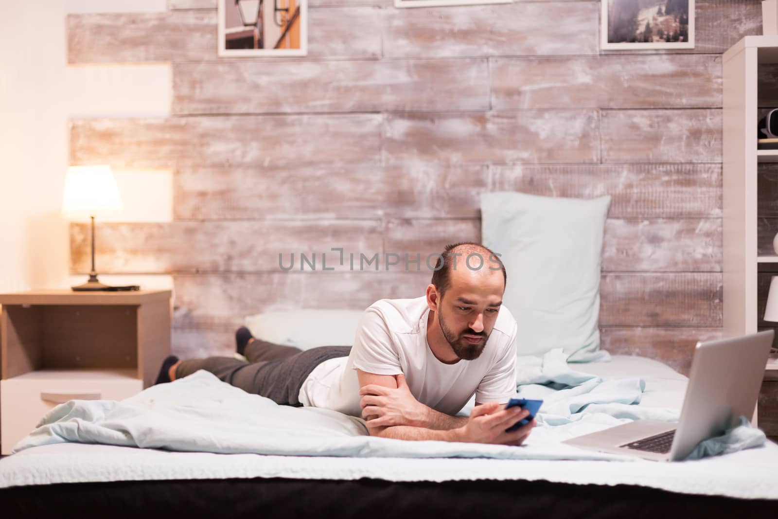 Using smartphone while laying on bed by DCStudio