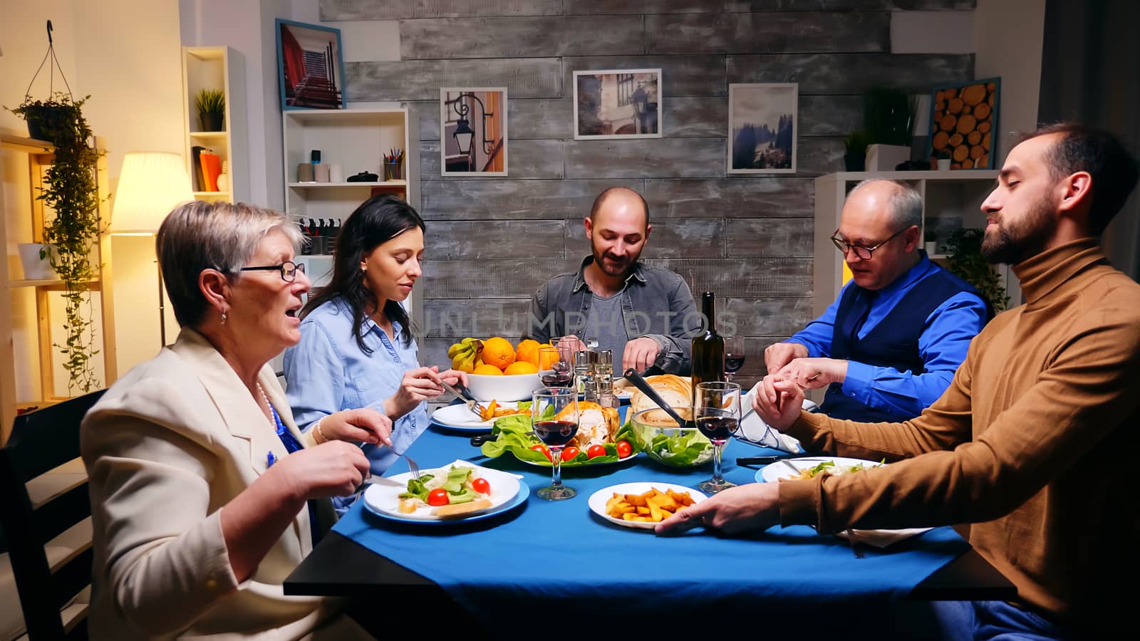 Zoom out shot of brother serving his sister with potatoes at family dinner.