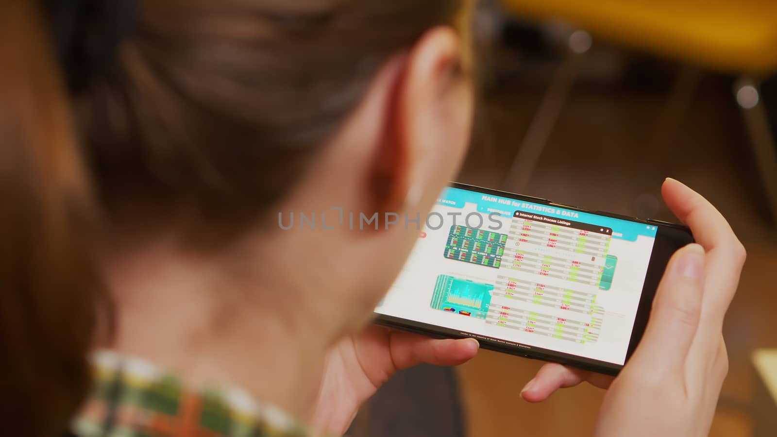 Back view of woman holding smartphone with financial currency. Stock market.