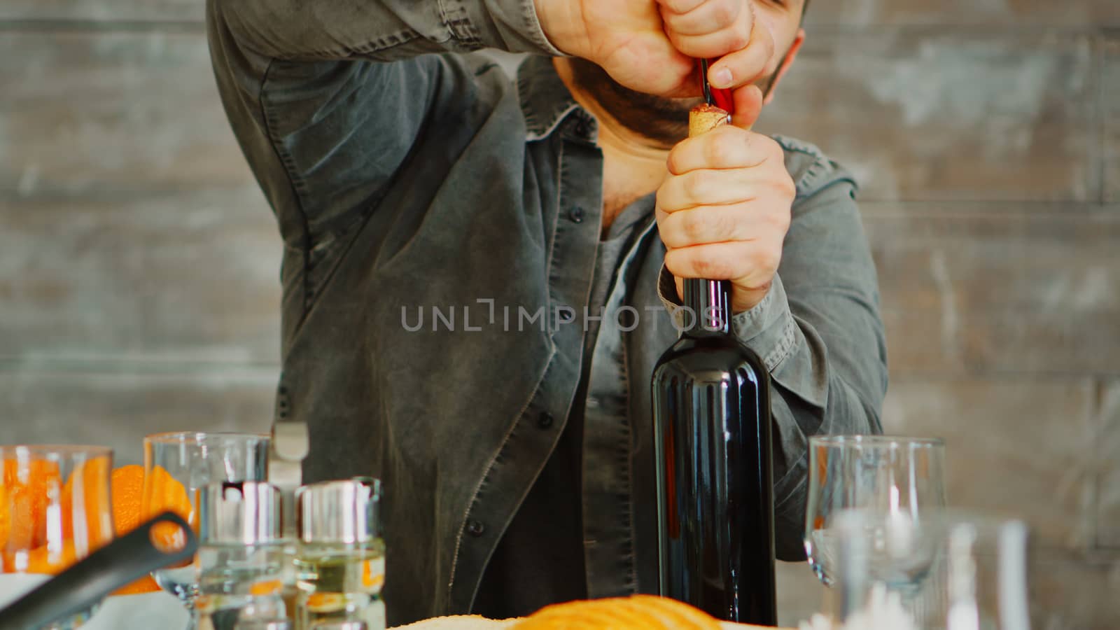 Close up shot of man opening a bottle of red wine for his family at lunch.