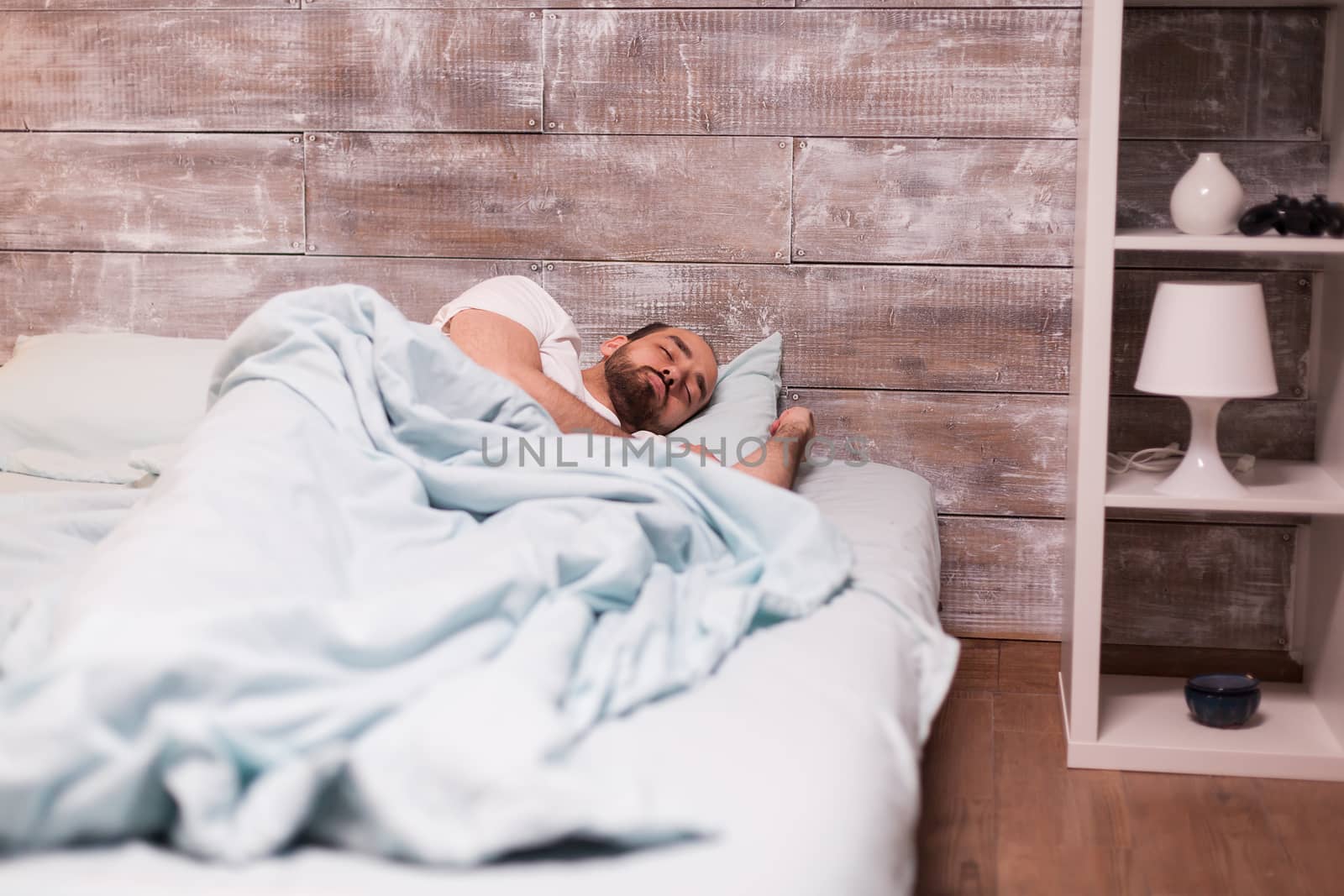 Man sleeping alone in his comfortable bed with peaceful face.