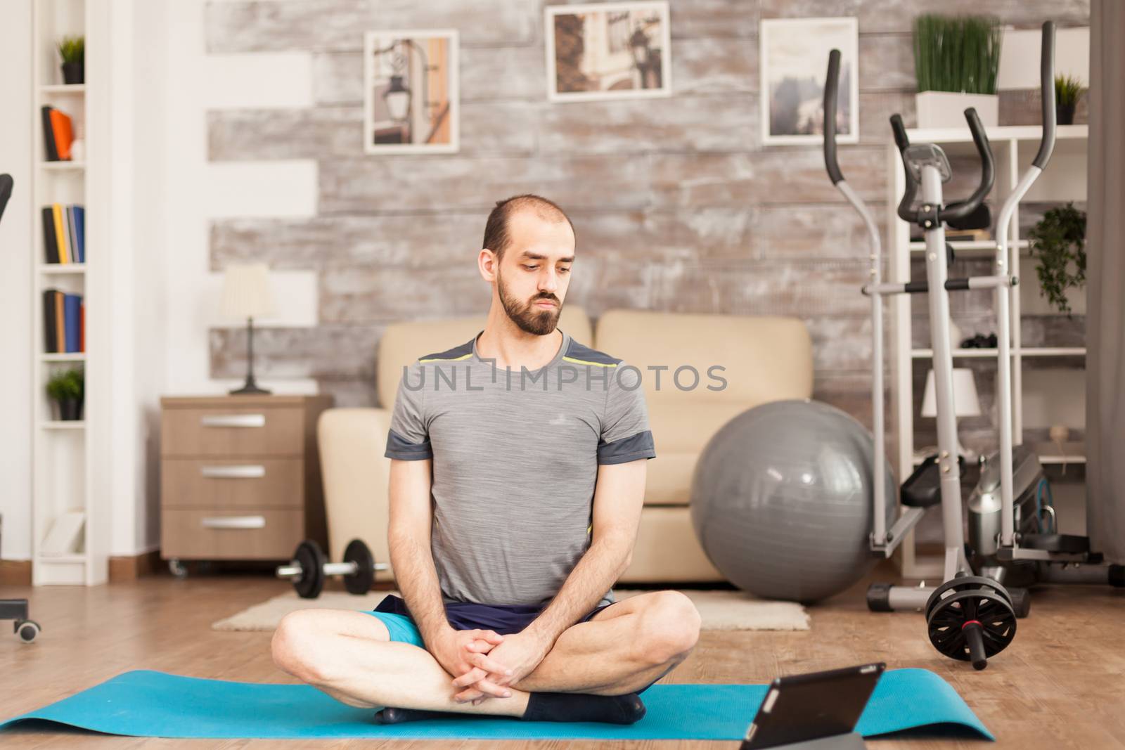 Man in shape watching online yoga class by DCStudio