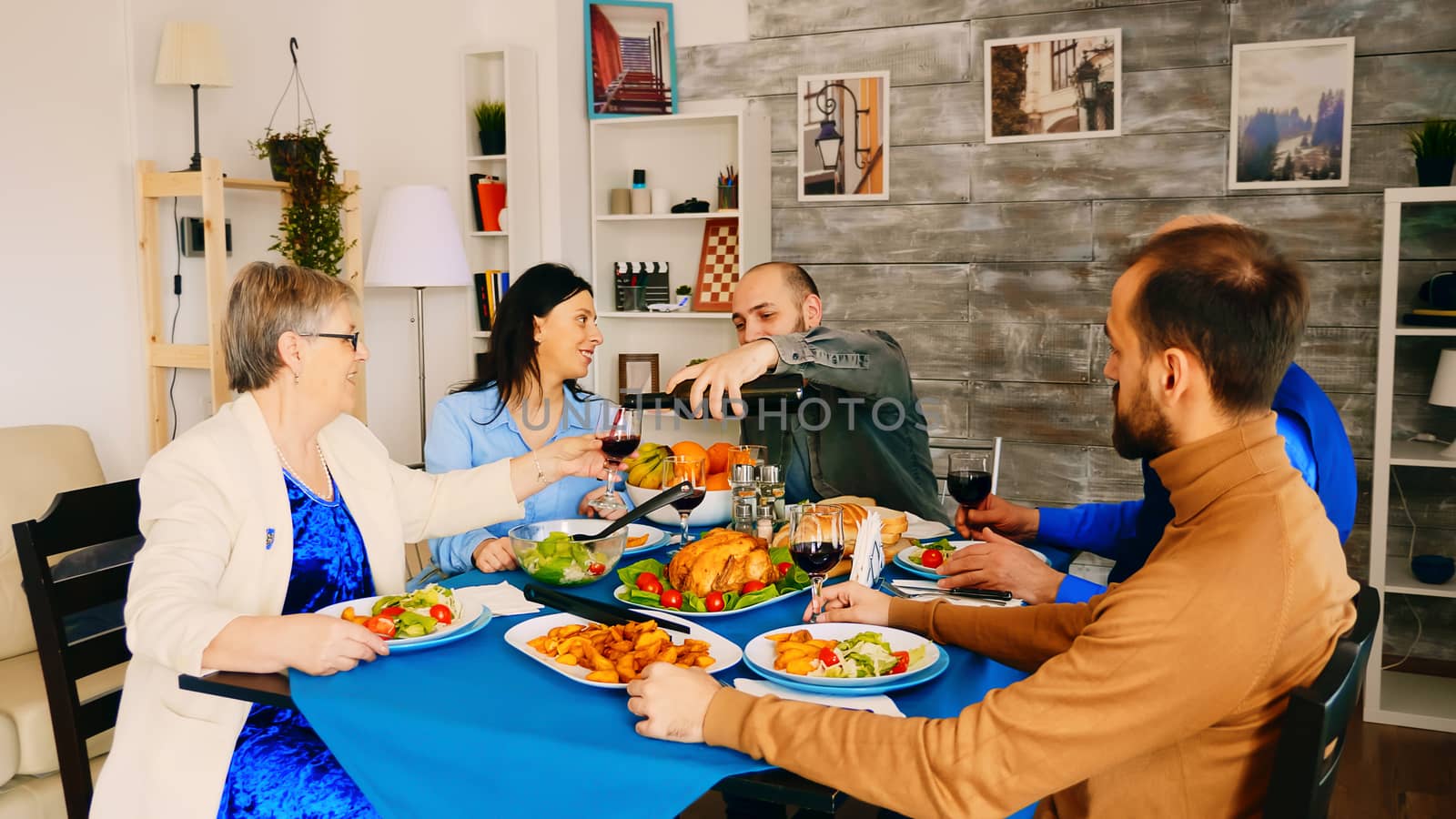 Young man pouring red wine to his mother at family dinner.
