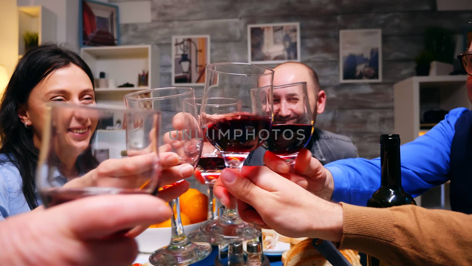 Zoom in shot of family clinking glasses of red wine by DCStudio