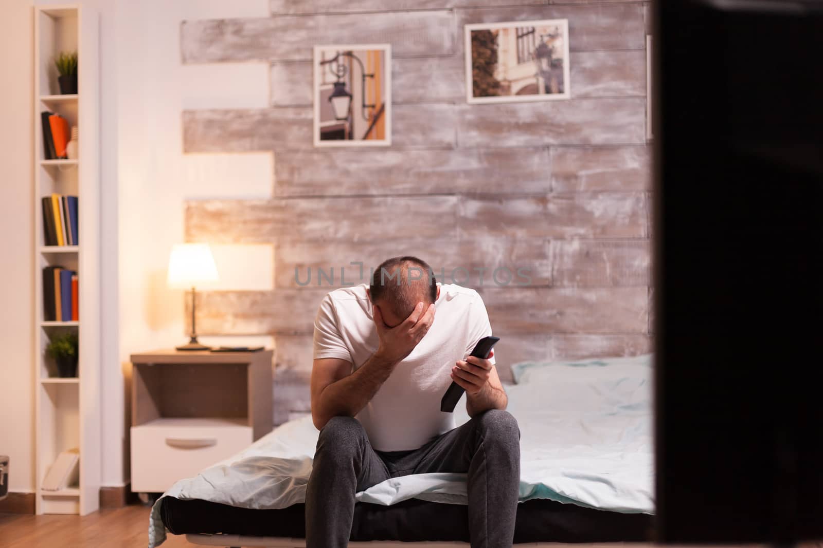 Cheerful man covering his face while watching a tv show at night.