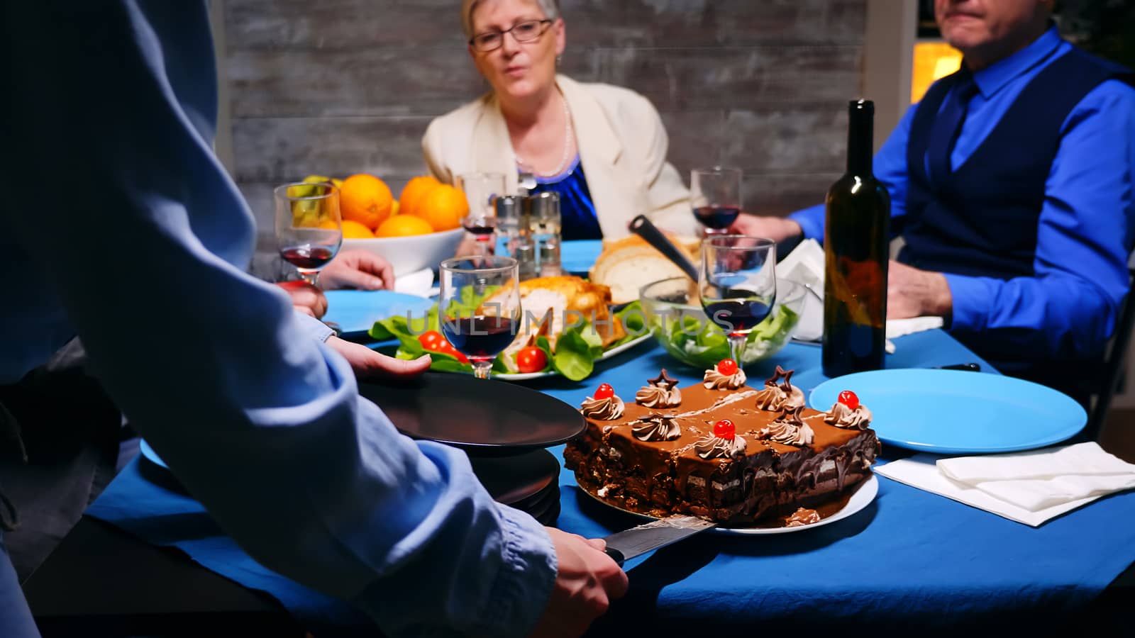 Follow shot of young woman giving her mother a slice of cake at family dinner.