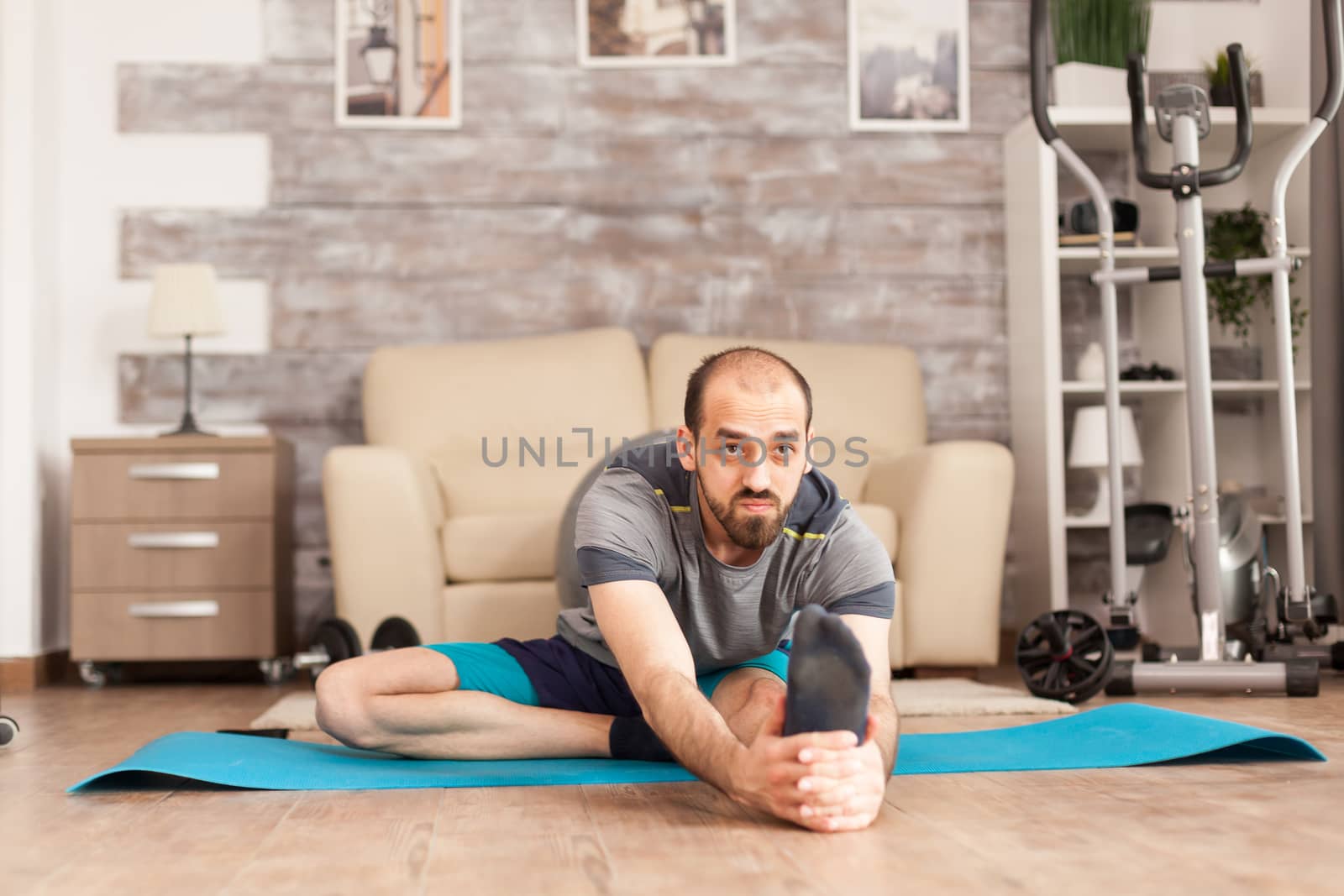 Healthy man doing mobily exercise on yoga mat at home during global pandemic.