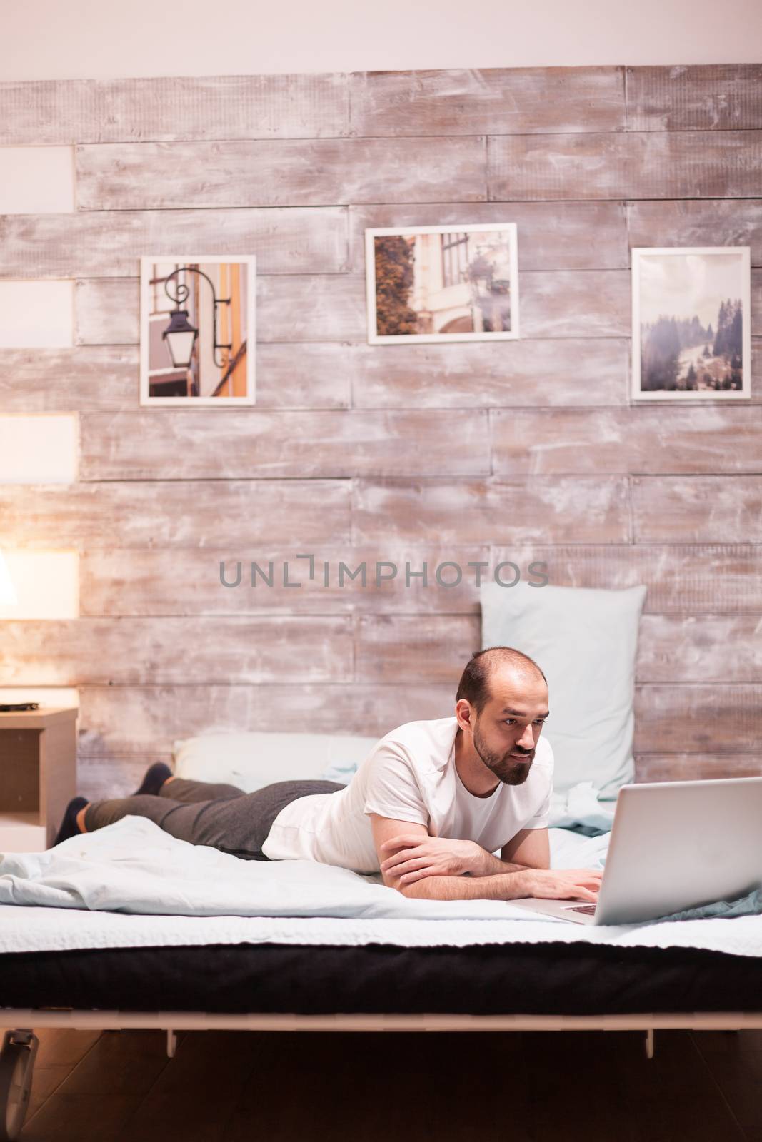 Freelancer working on laptop at night while laying in bed