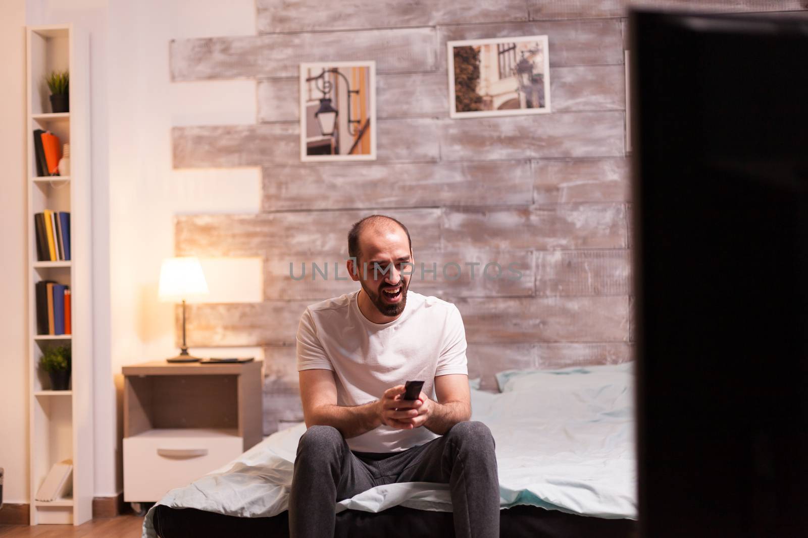 Man holding tv remote control while laughing during a tv show.