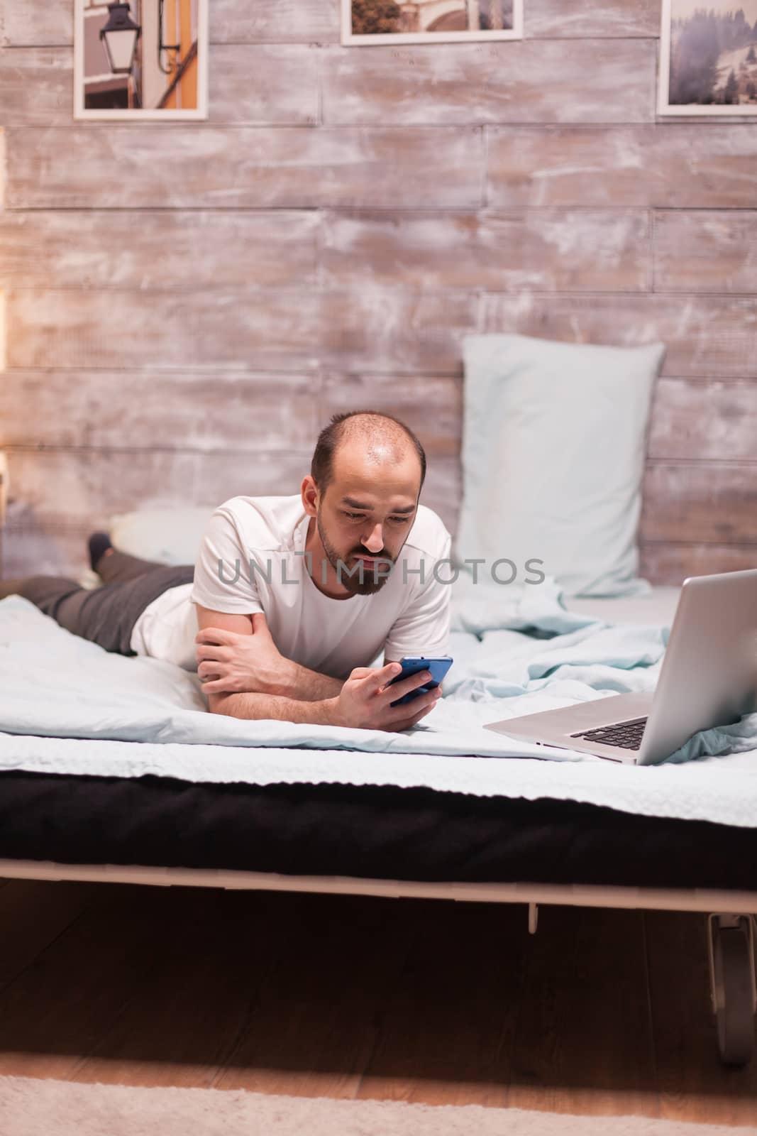 Man laying in bed in wearing pajamas by DCStudio