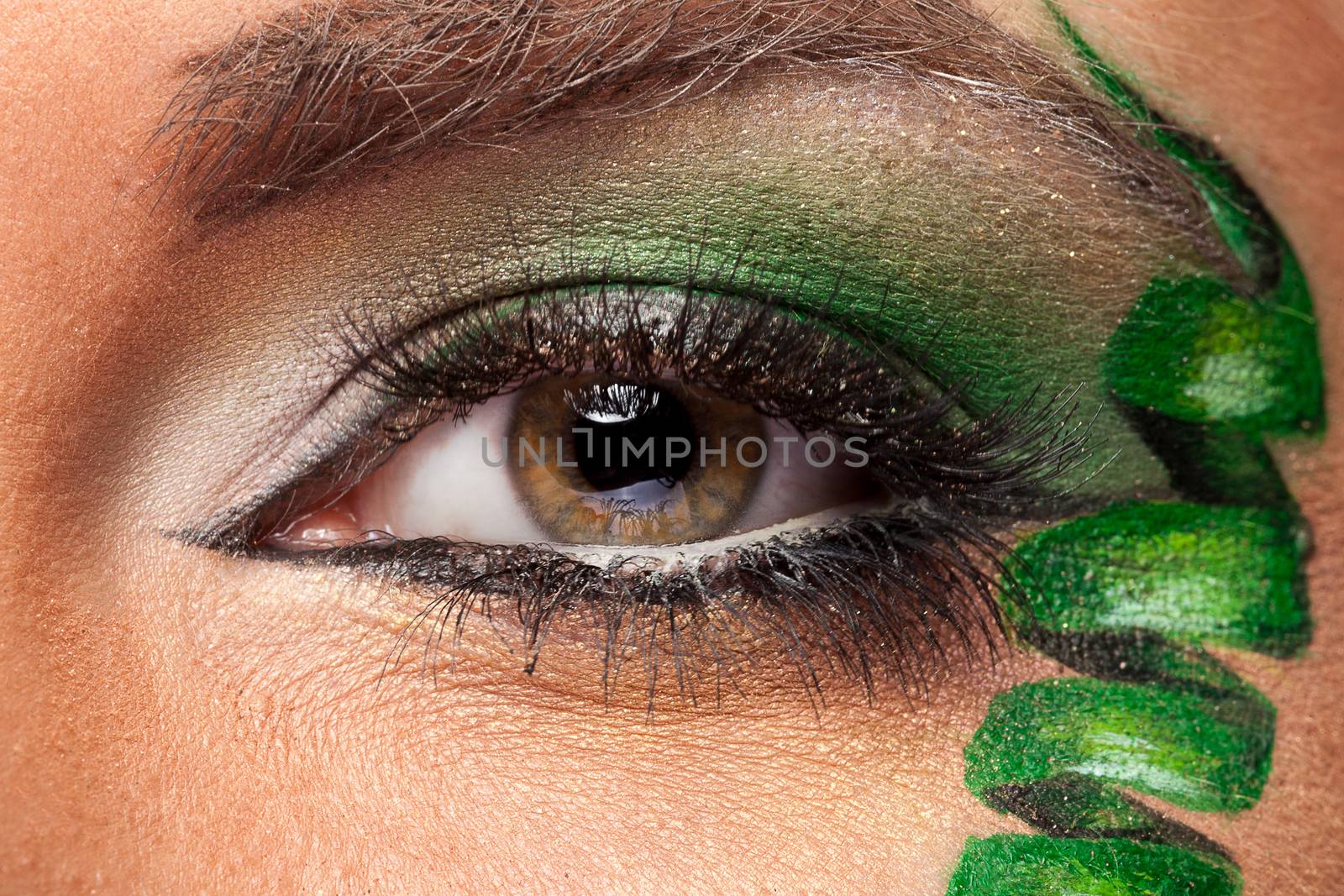 Close up of an eye with green artistic make up in studio photo