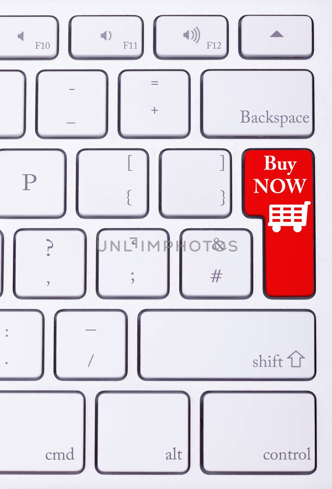 Red button on keyboard with buy now words on it and a shopping cart. E-commerce and online sales