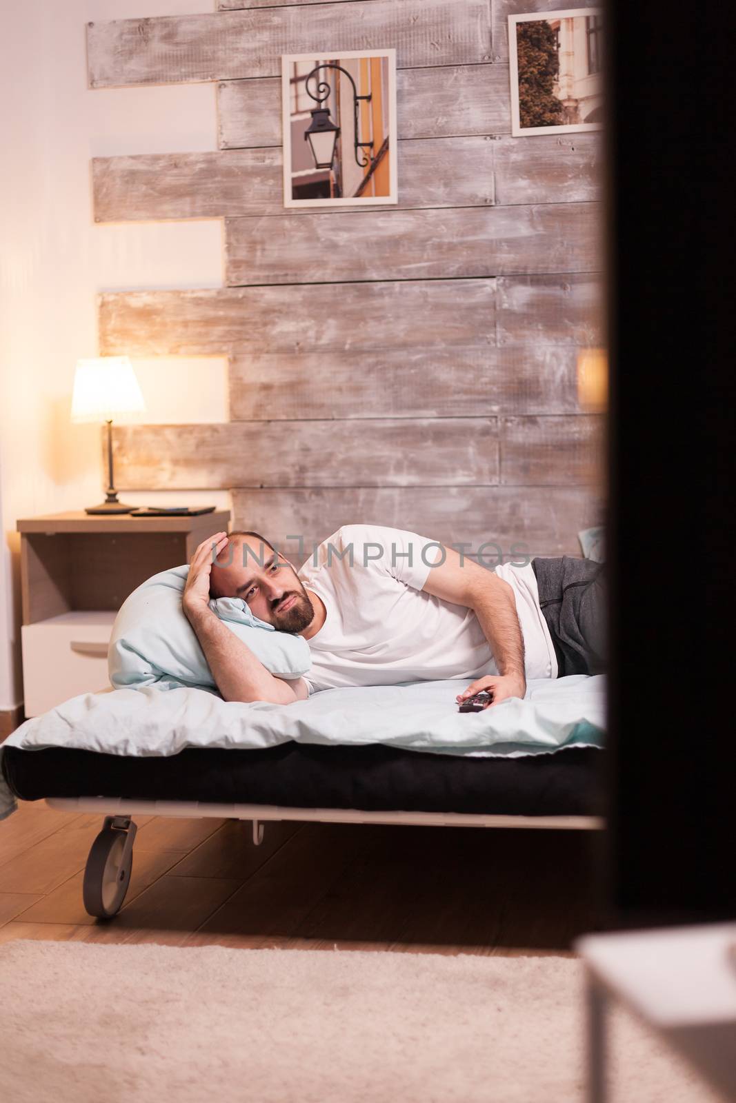 Man suffering of insomnia watching a tv show late at night.