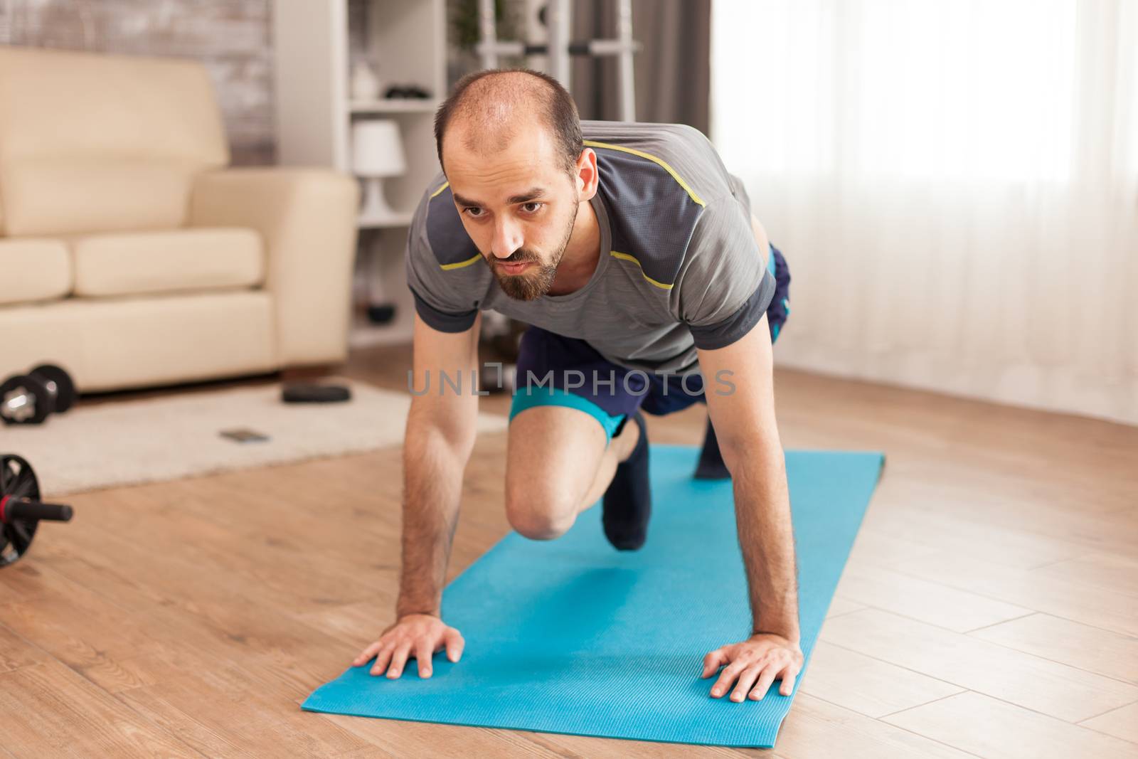 Fit man working his body on yoga mat during self isolation.