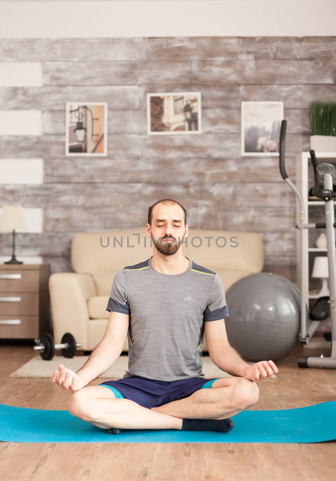 Man keeping his eyes closed doing yoga at home during covid-19 lockdown.