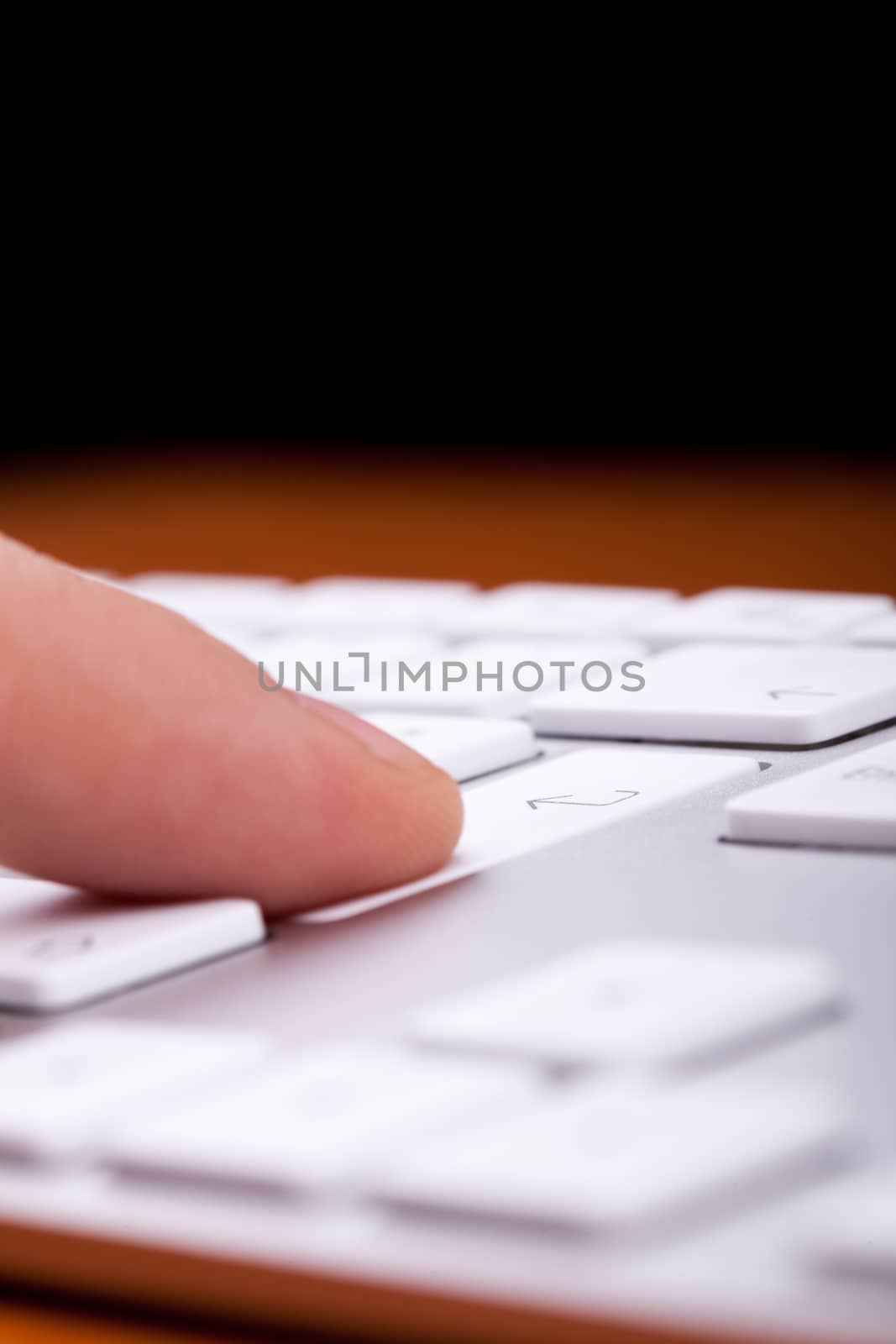 Finger pressing an enter button on alluminium keyboard with black copy space on top of it