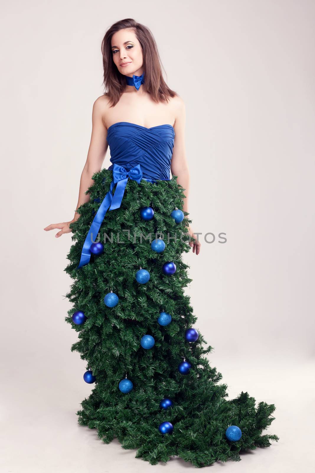 Woman in christmas tree dress on grey background by DCStudio