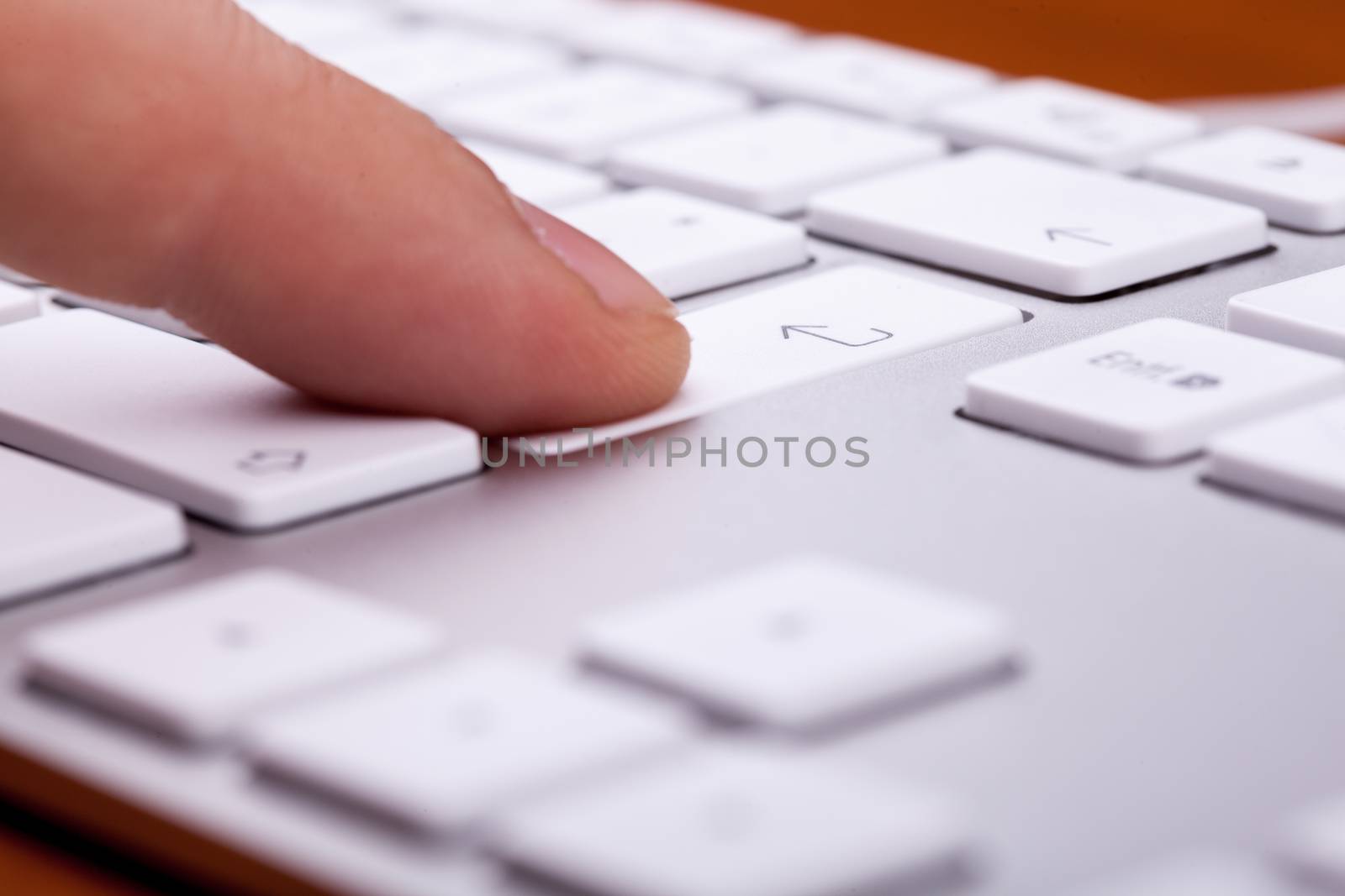 Finger pressing on keyboard key in close up