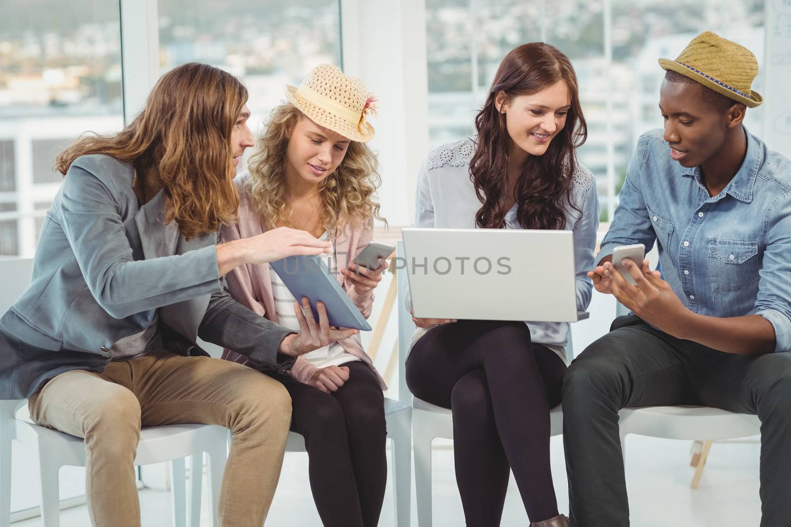 Business people using technology while discussing in creative office