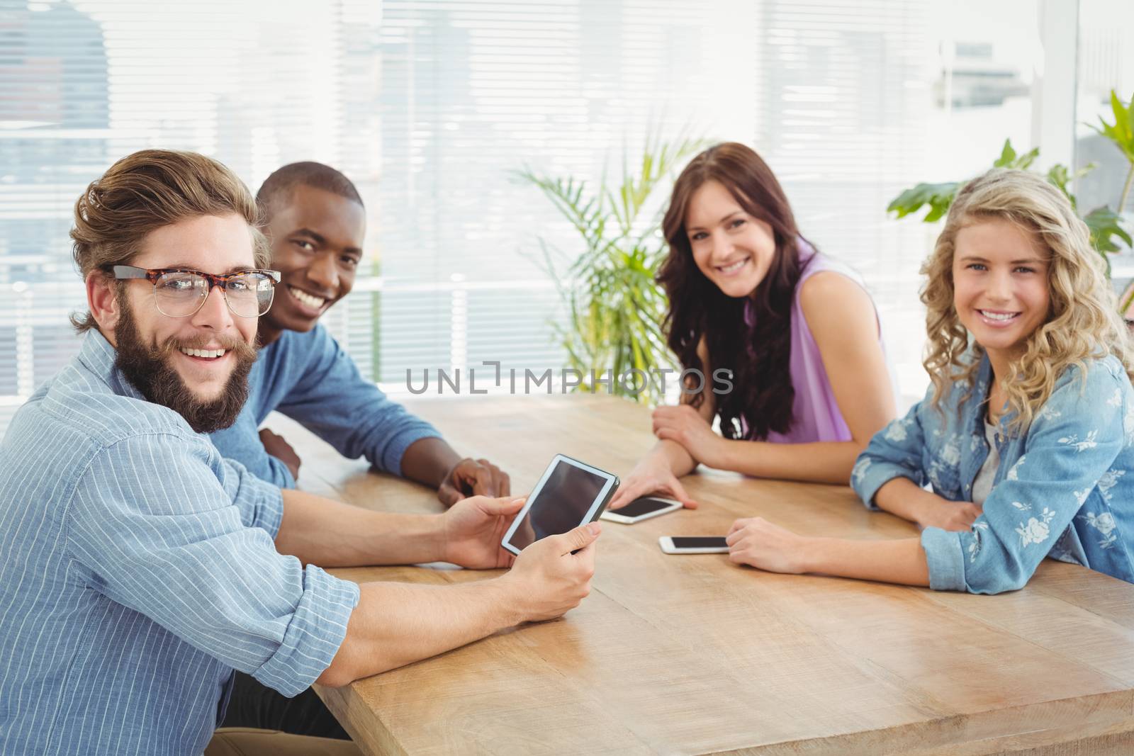 Portrait of smiling business professionals using technology at desk in office
