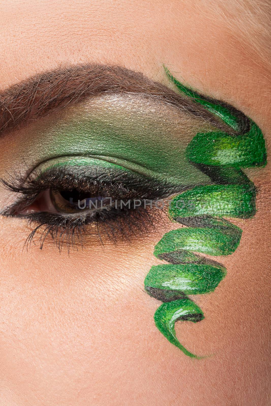 Close up of an eye with green artistic make up in studio photo