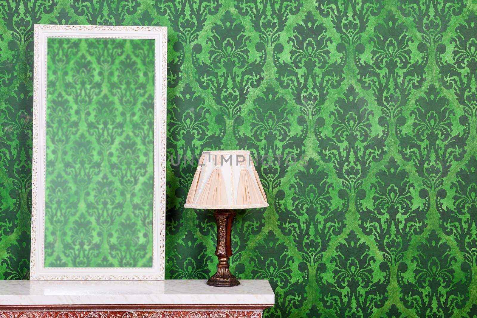 Old vintage mirrod in woden frame on chimney on green vintage pattern background
