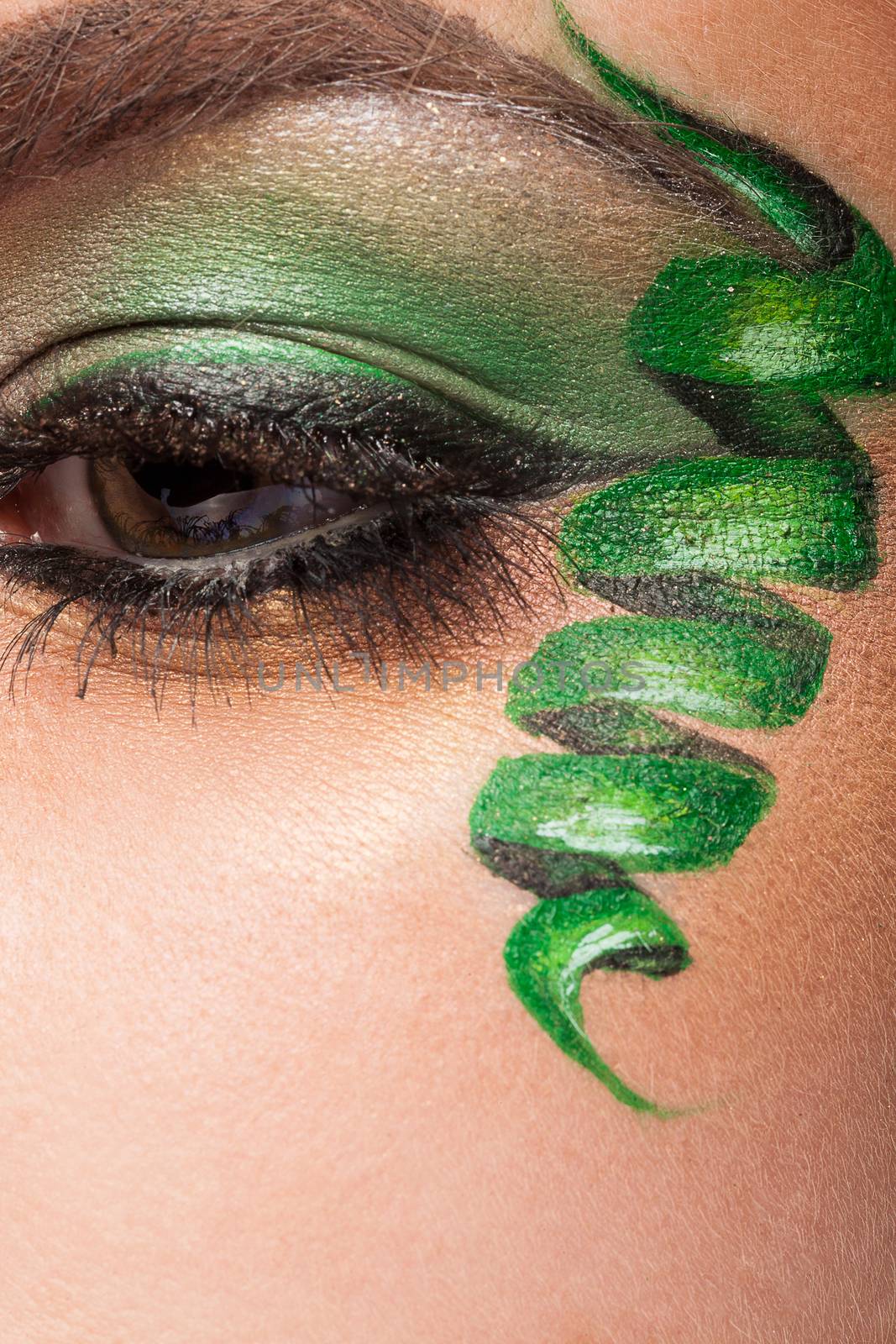 Close up of an eye with green artistic make up in studio photo