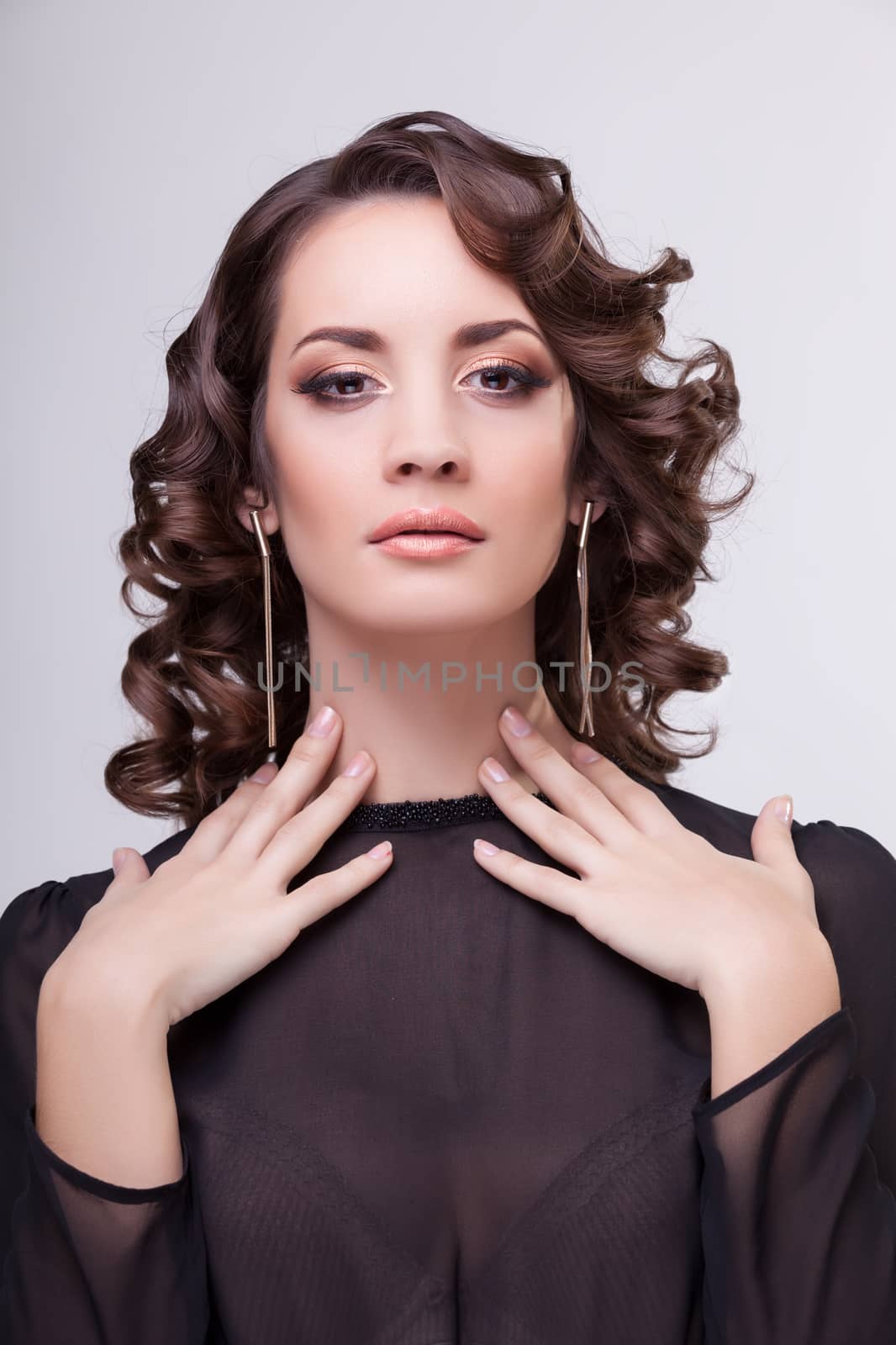 Sensual woman with hands on her neck. Professional make up and hairstyle. Studio lighting