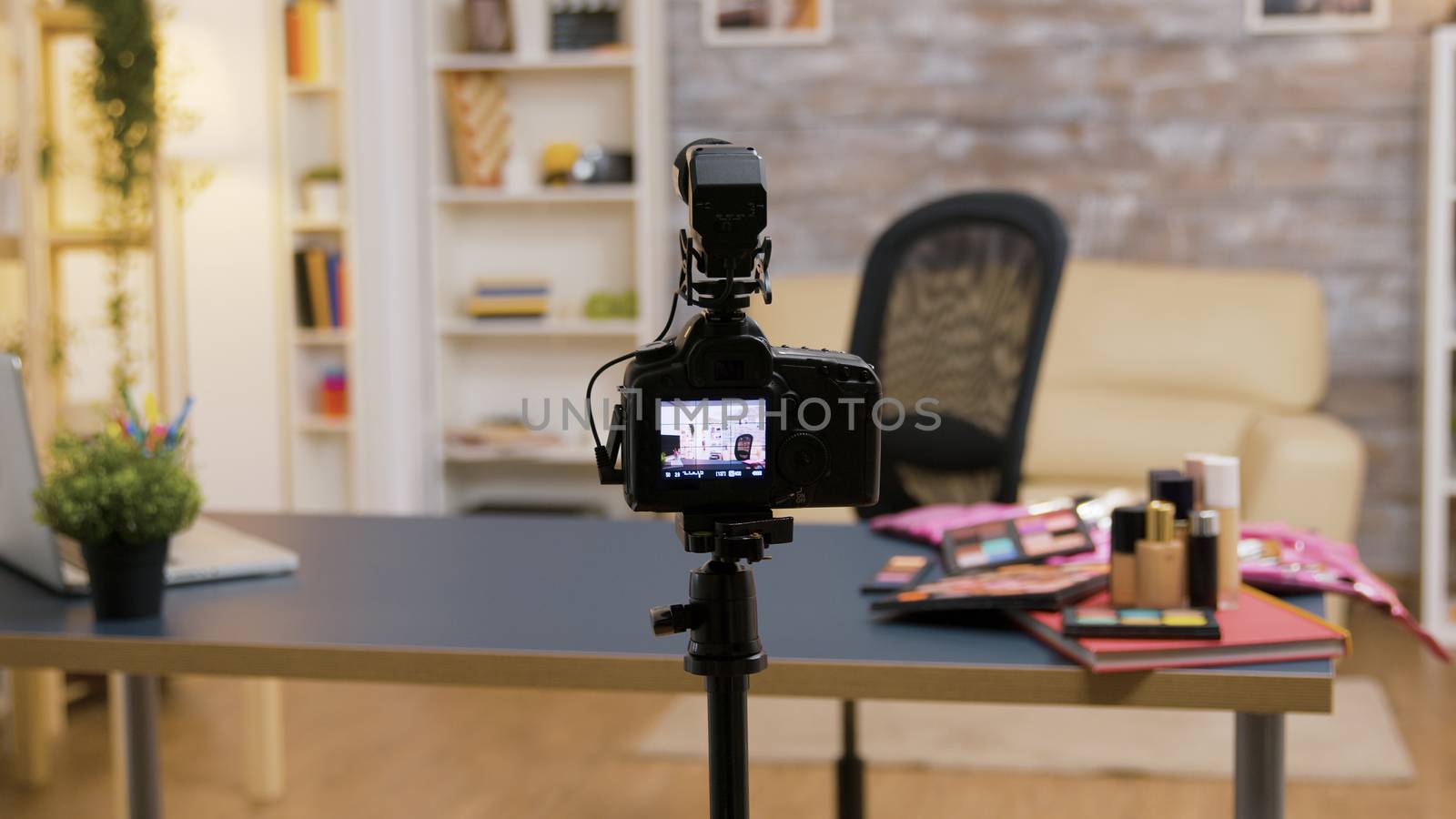 Zoom in shot of empty influencer room with cosmetics on the table and professional recording equipment.
