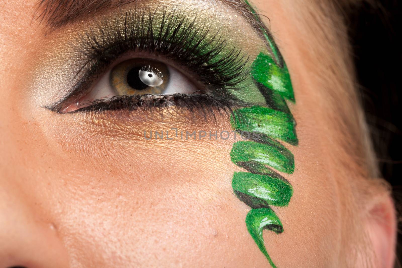 Close up of an eye with green artistic make up in studio photo