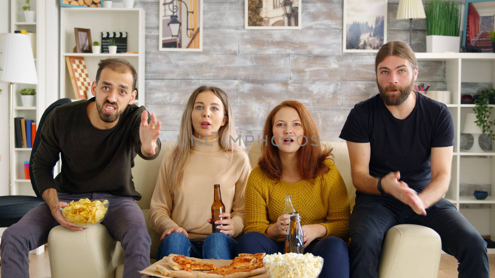 Girl scared by a bug while watching movie with her friends in living room eating pizza and drinking beer.