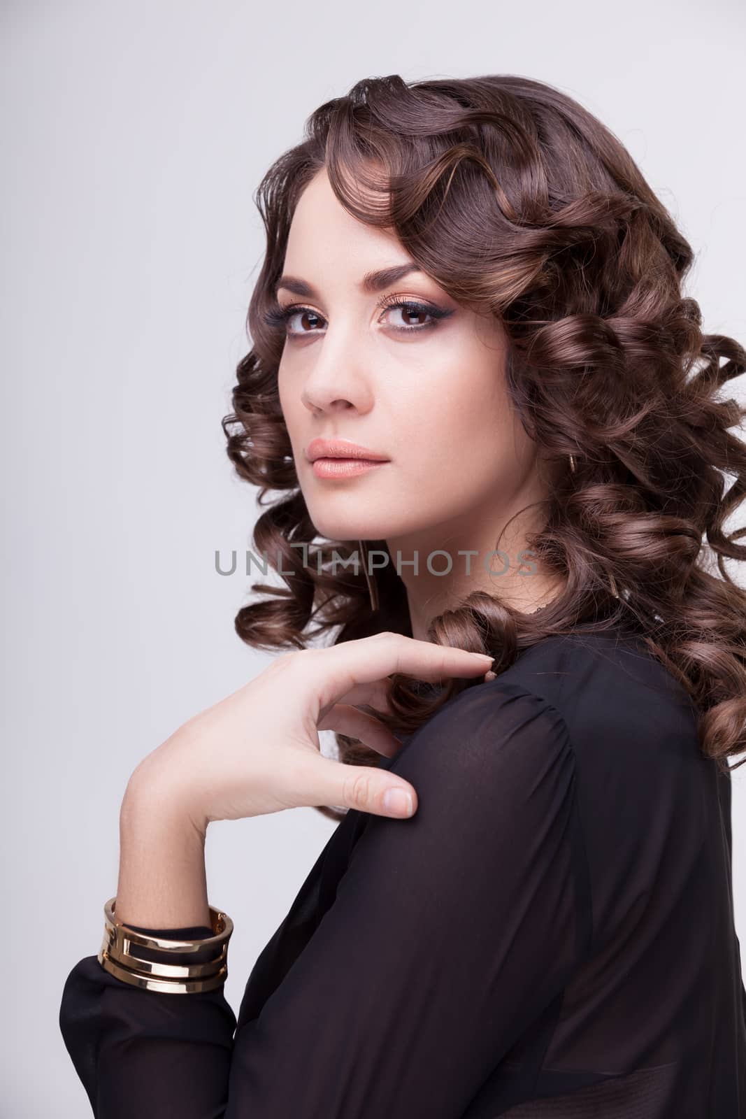 Gorgeous woman professional make up and hairstyle on grey background. Studio shooting