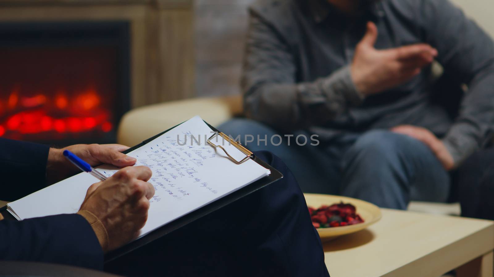 Close up of psychologist writing notes while couple yelling at relationship guidance.