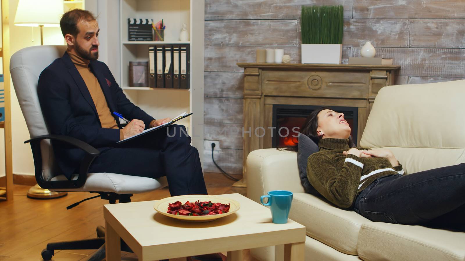 Psychotherapist taking notes while unhappy woman by DCStudio