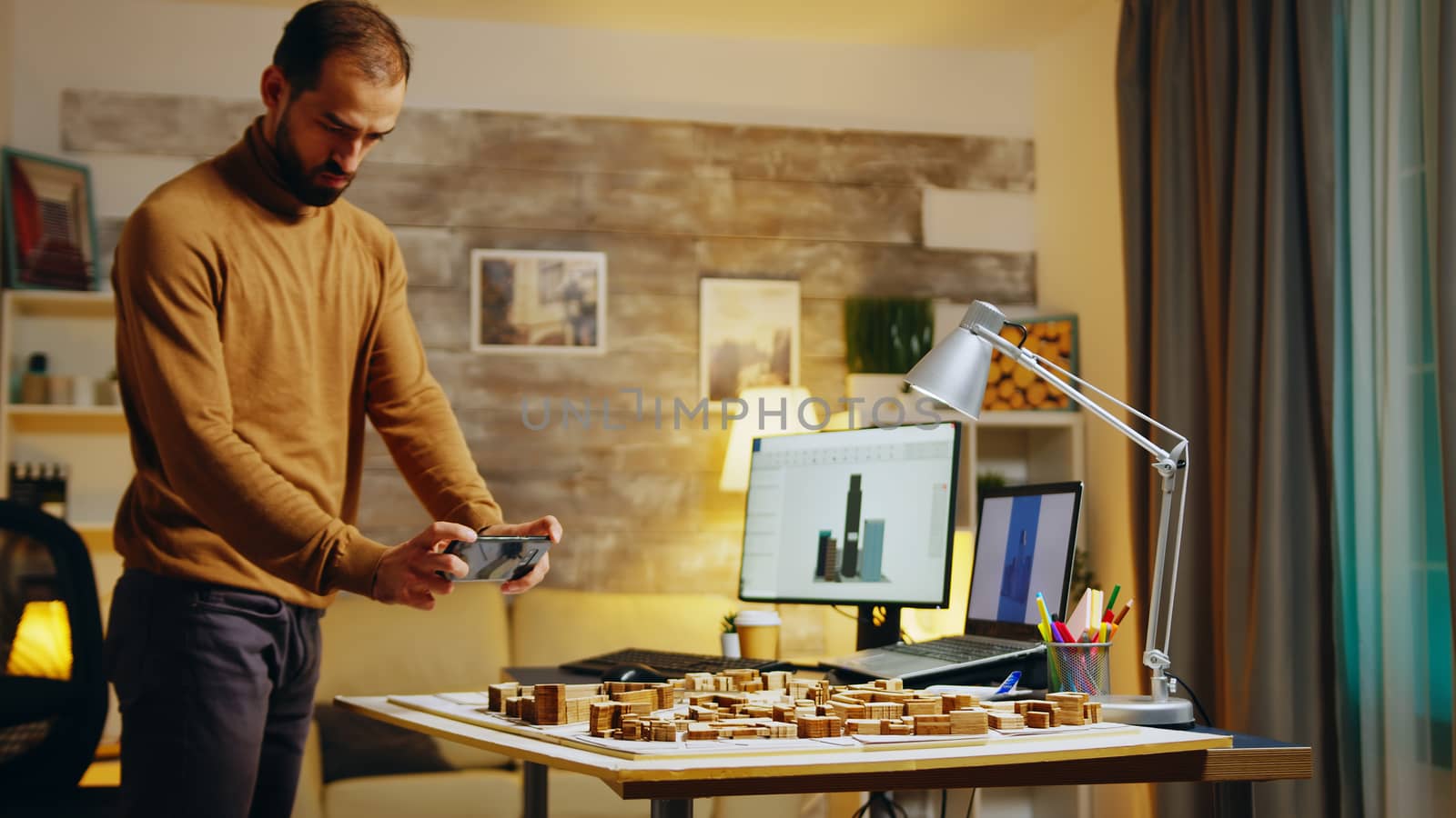 Successful architect taking photos with his phone of building models.