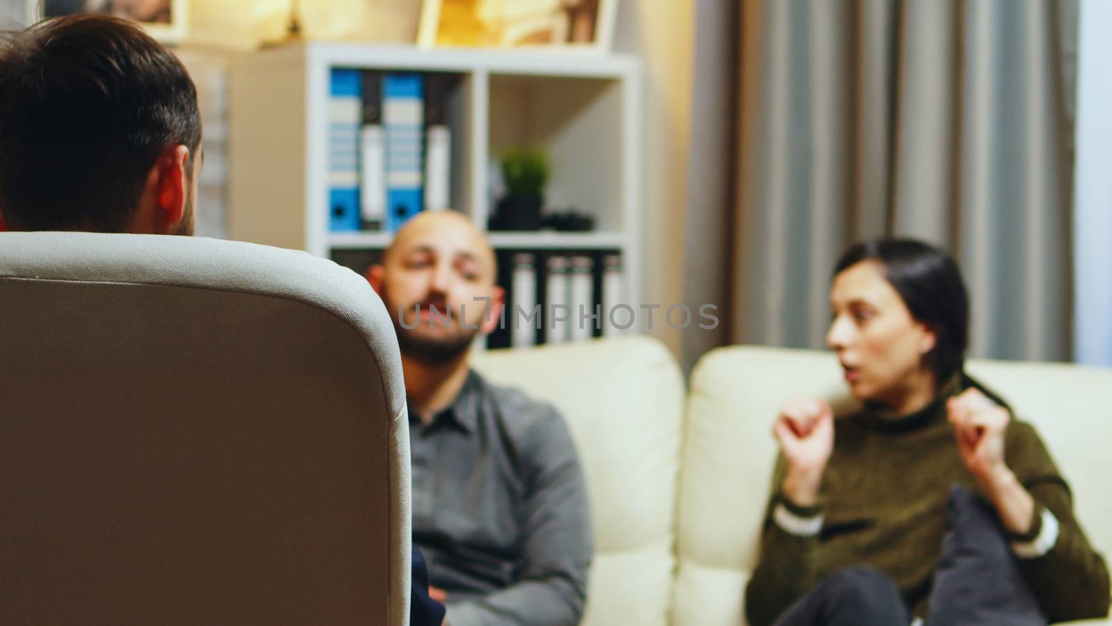 Back view of relationship therapist counseling young couple about their relationship.