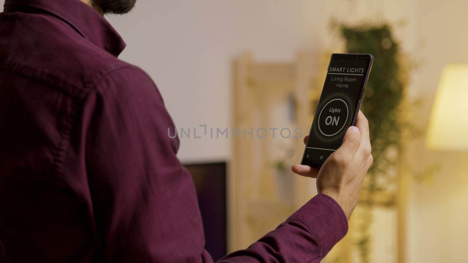 Man holding a smartphone with voice activation smart light app to turn on the lights in the house. Future technology and smart application