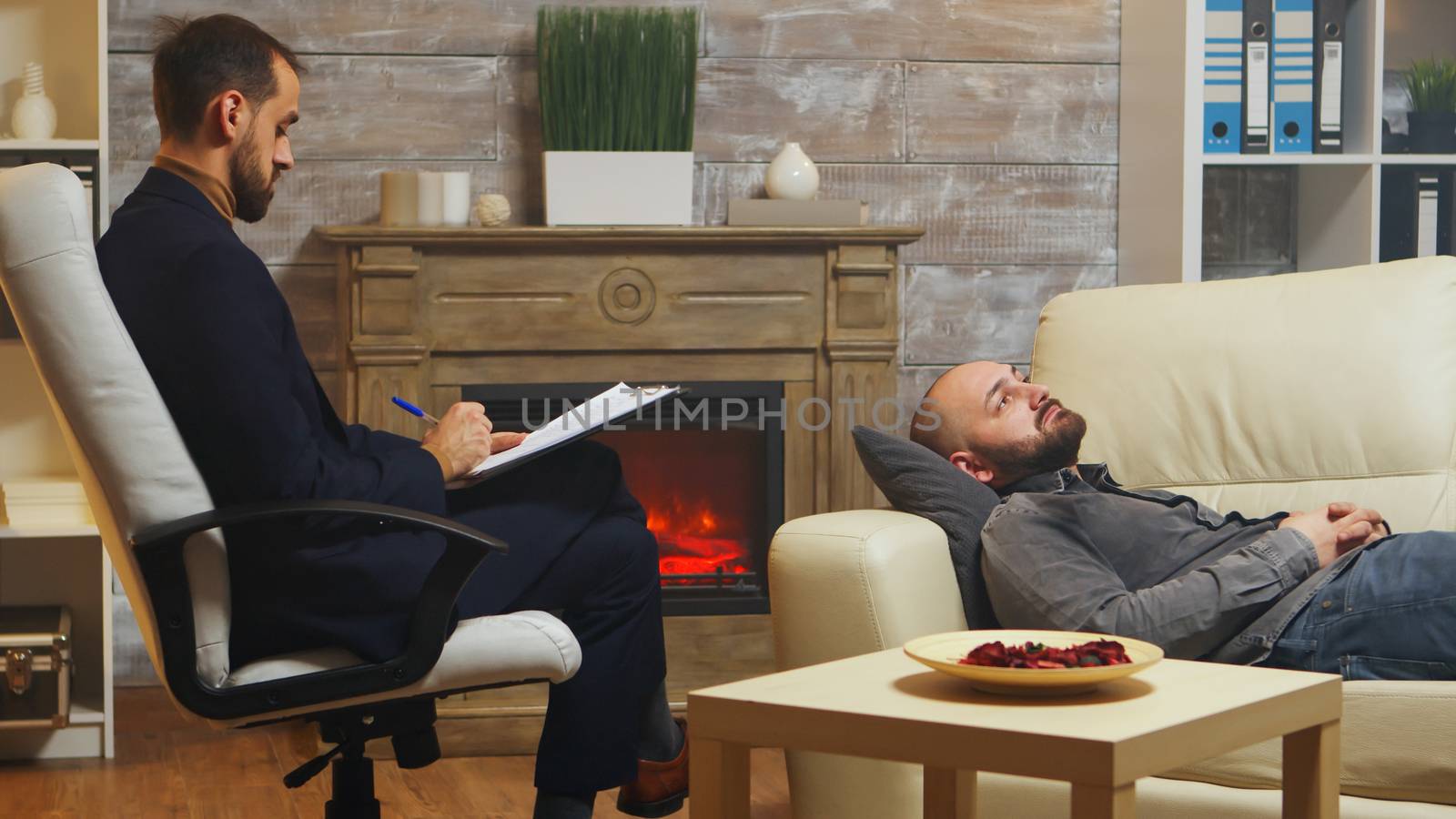 Bearded man laying down on couch at couple therapy by DCStudio