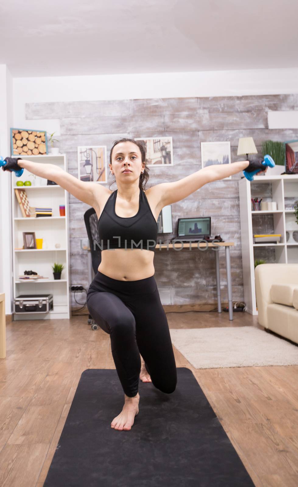 Young caucasian woman doing lunges at home using dumbbells.