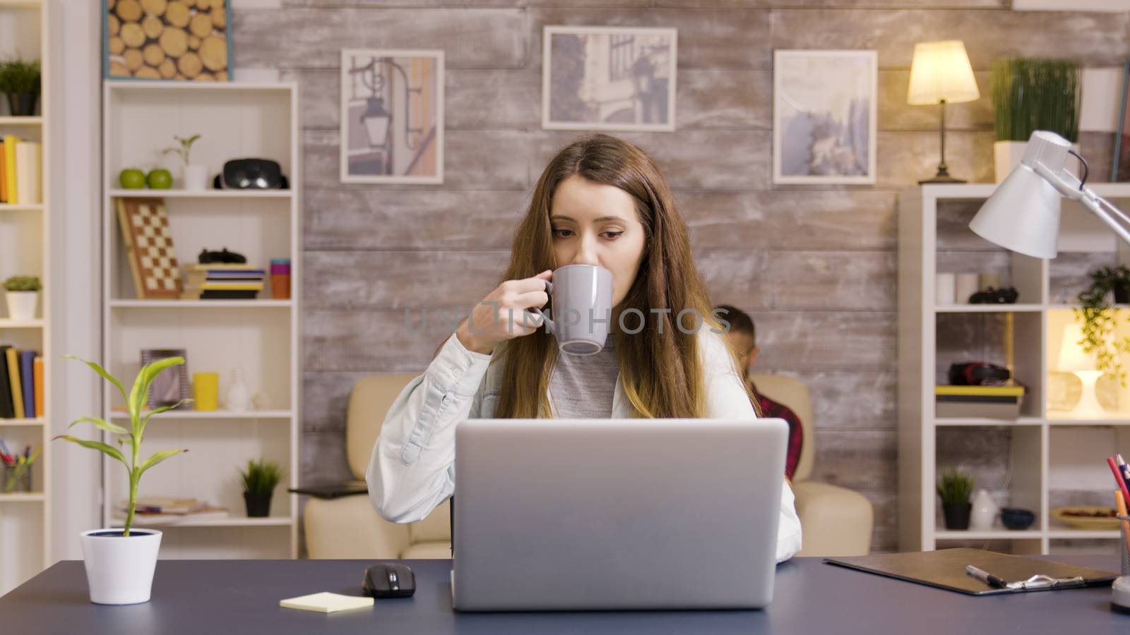 Beautiful young female working on laptop in home office. Young freelancer working from home.