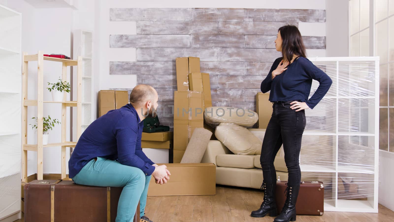 Young couple arriving with suitcases in their new apartment. Cardboard boxes in the background.