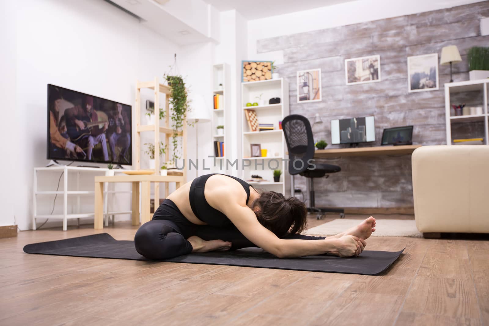 Side view of caucasian woman sitting on knee forward bend yoga exercise in living room.