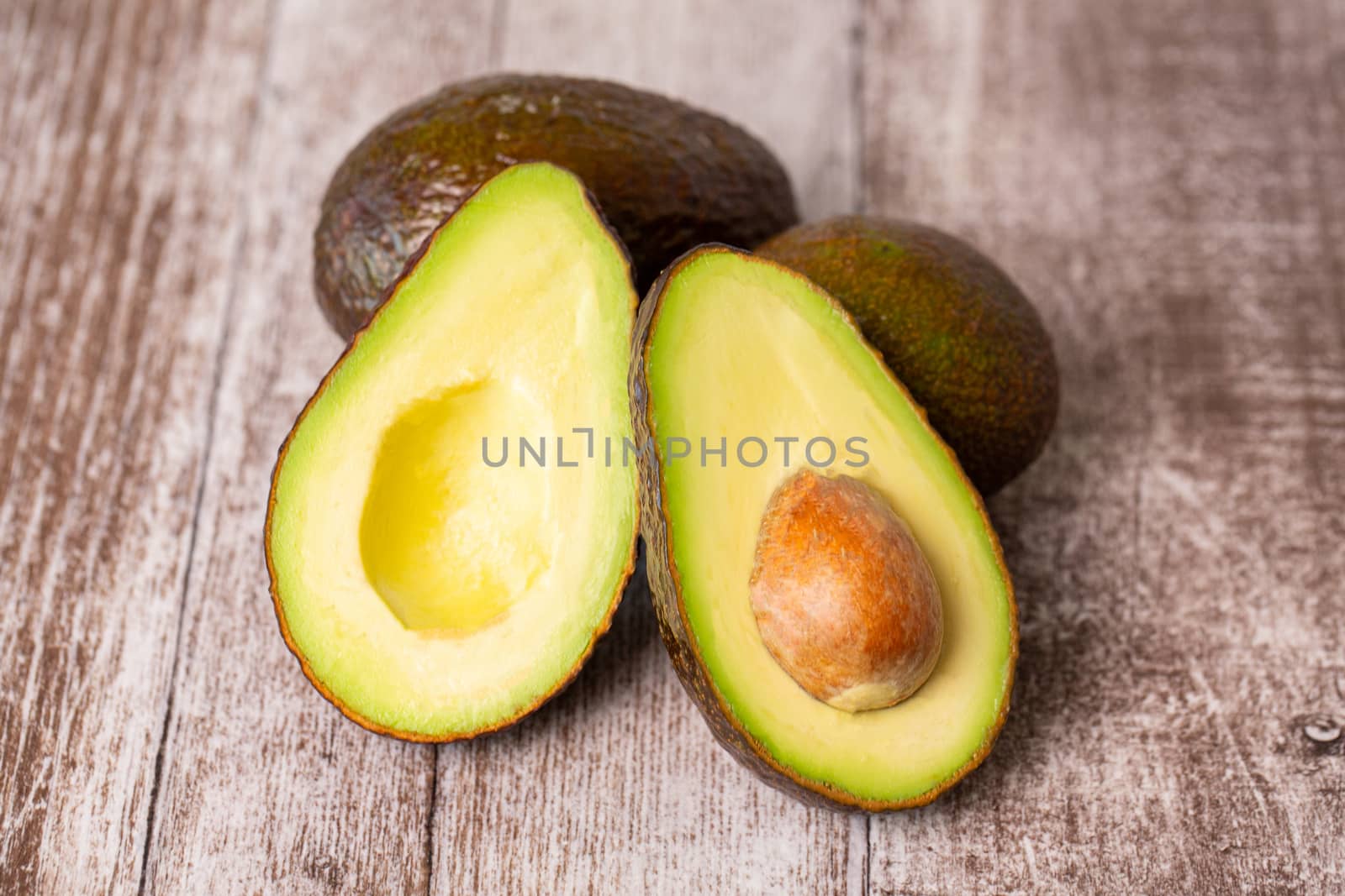 Avocado composition cutted in half on a wooden board.