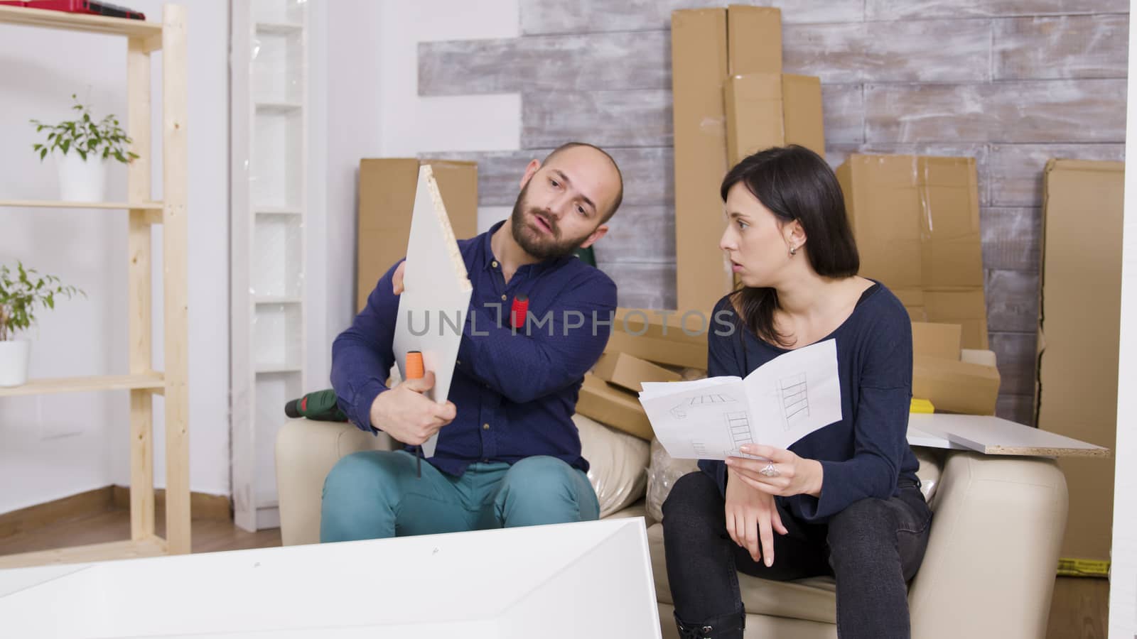 Couple assembling furniture using instructions in their new apartment. Couple working as a team.
