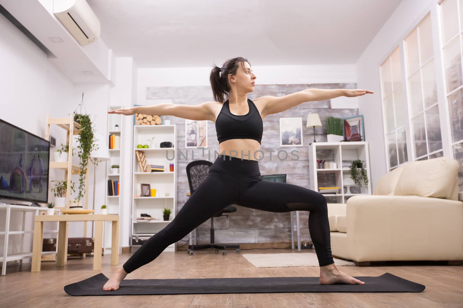 Attractive caucasian woman doing virabhadrasana yoga pose.